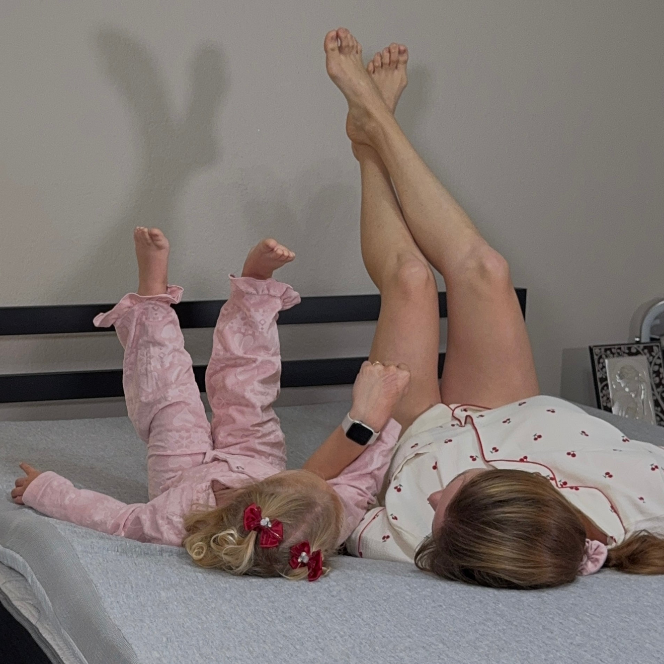 Two children playing on a bed with a gray mattress topper in a bedroom setting.